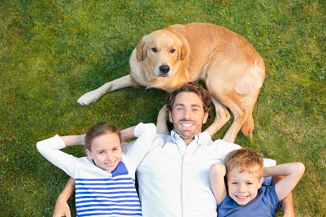 Family relaxing with dog on lawn