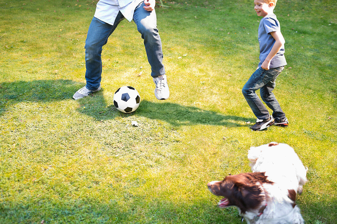 Boy playing soccer with dog outdoors