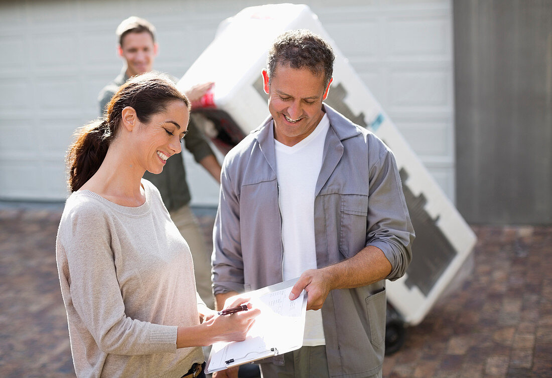 Woman signing for delivery in driveway