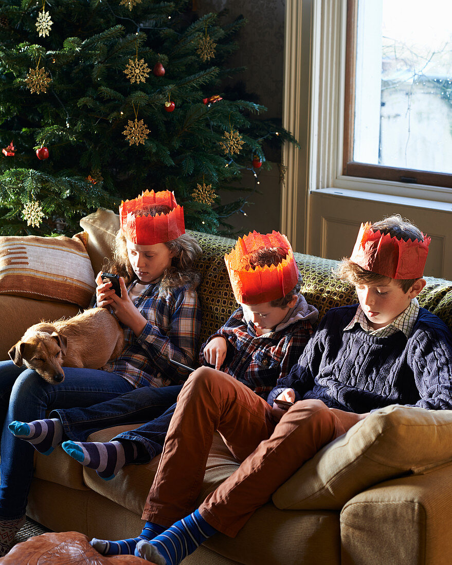 Children in paper crowns relaxing on sofa