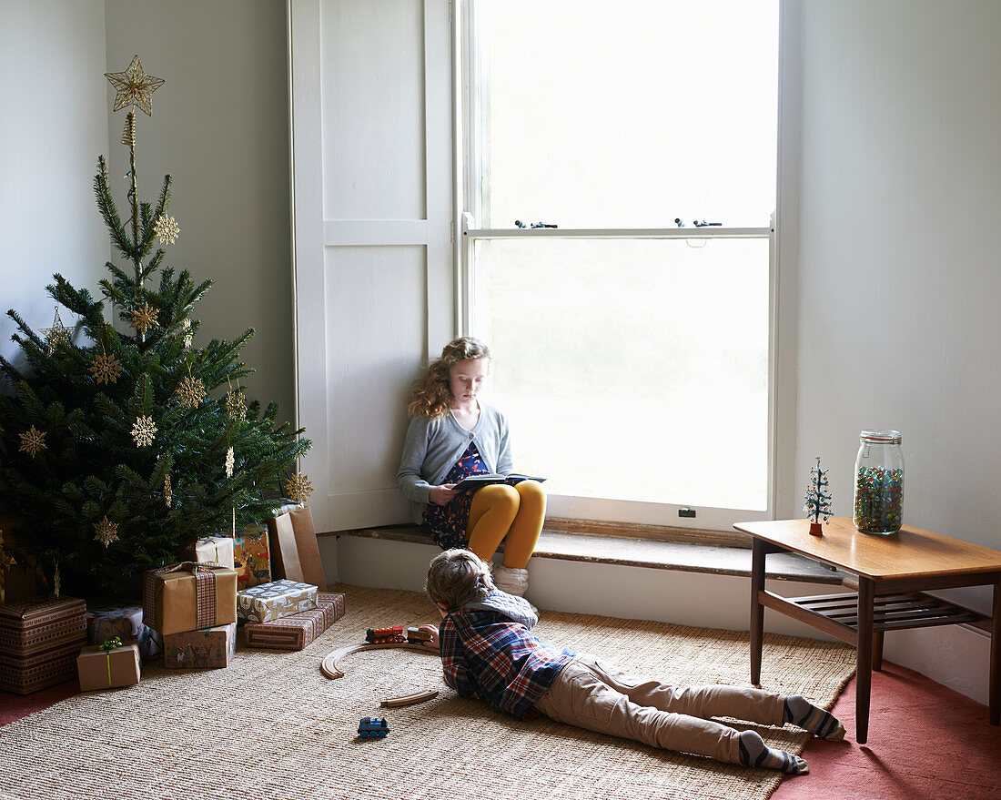 Children relaxing by Christmas tree