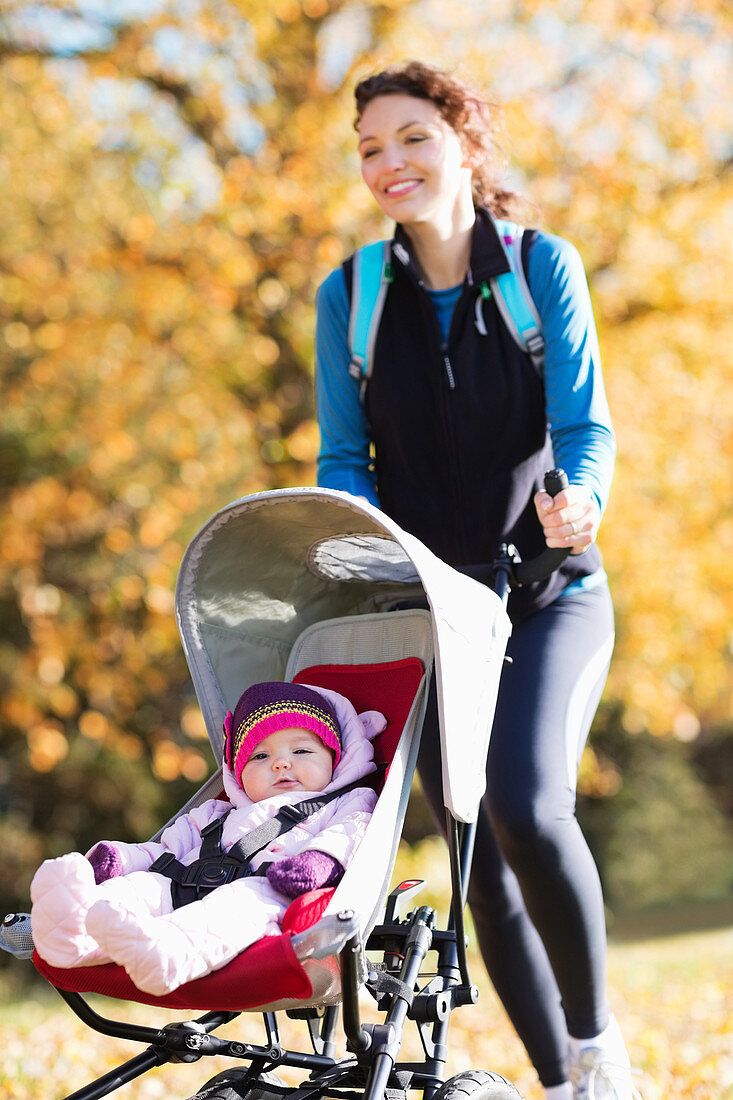 Woman running with baby stroller in park