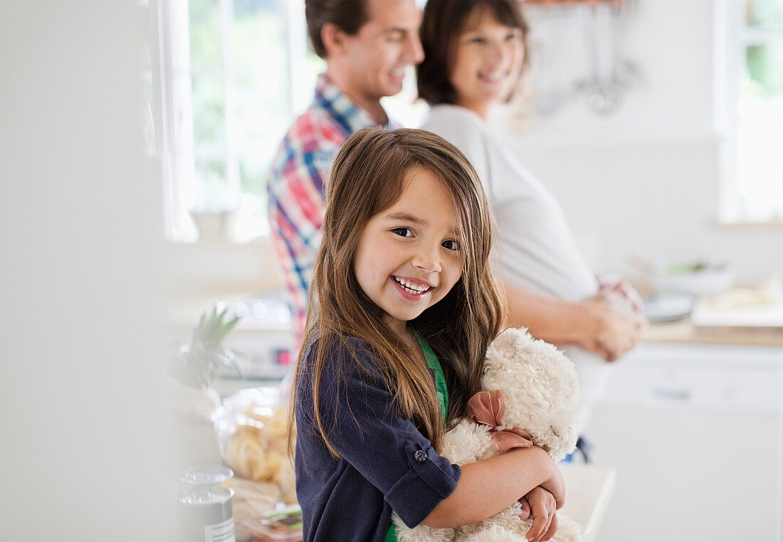 Girl holding teddy bear in kitchen