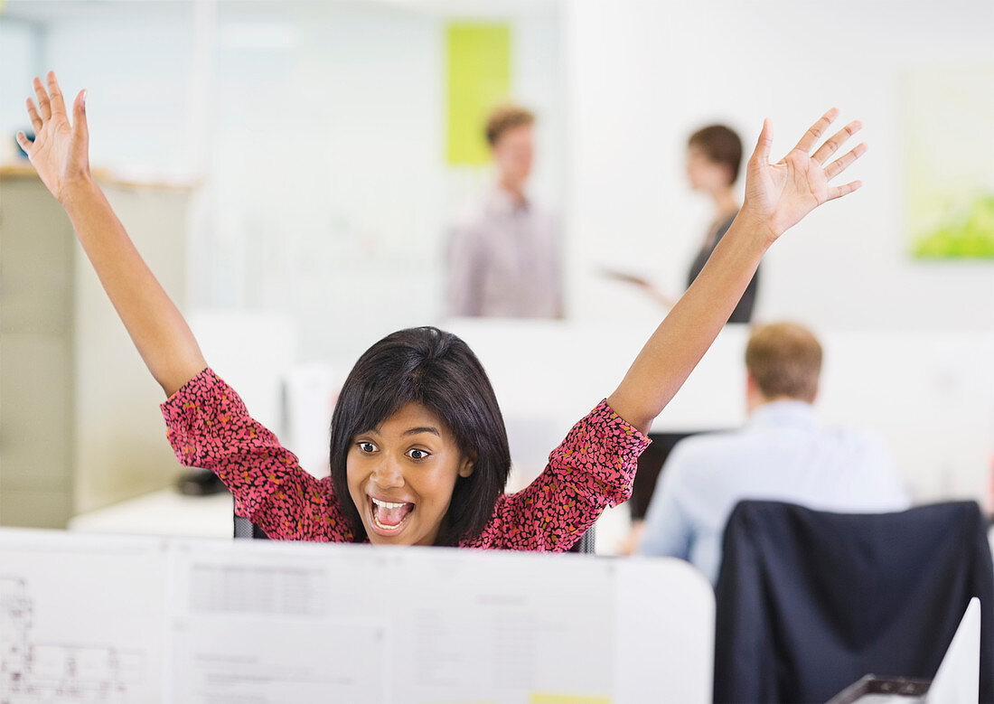 Businesswoman cheering at desk