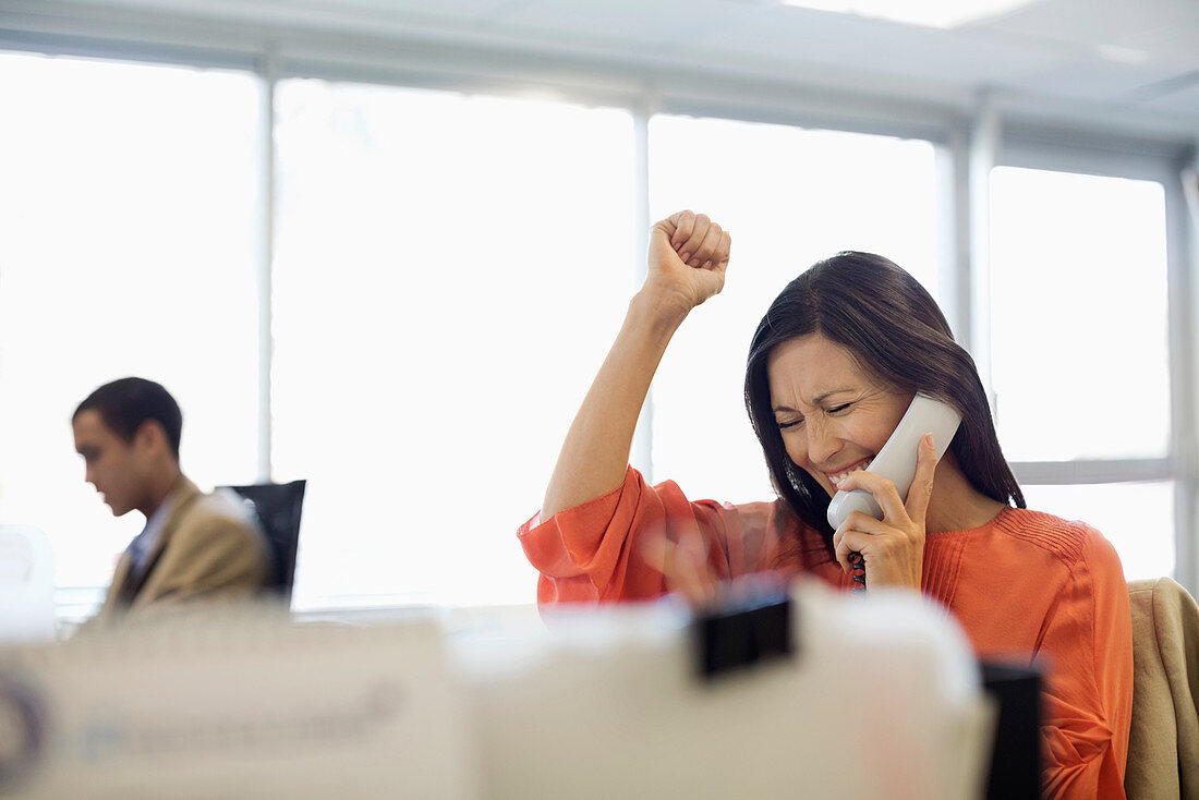 Businesswoman cheering at desk in office
