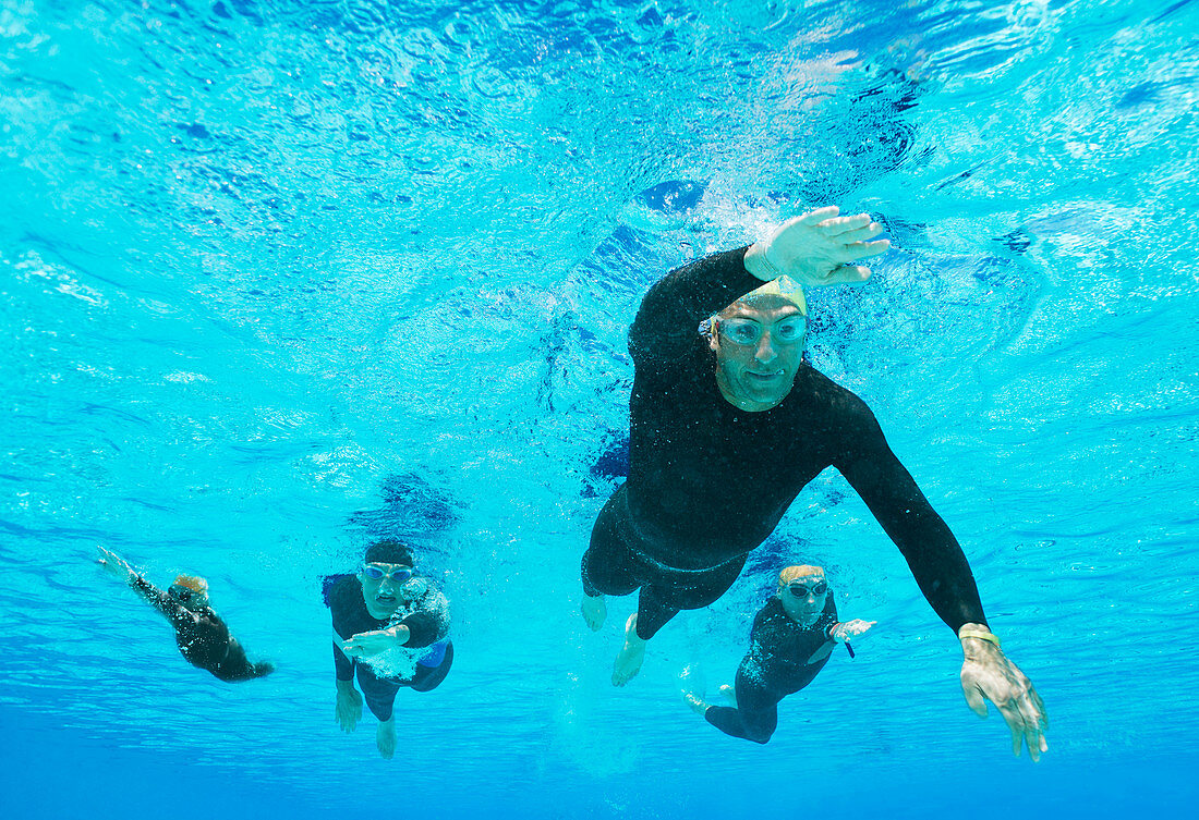 Triathletes in wetsuits underwater