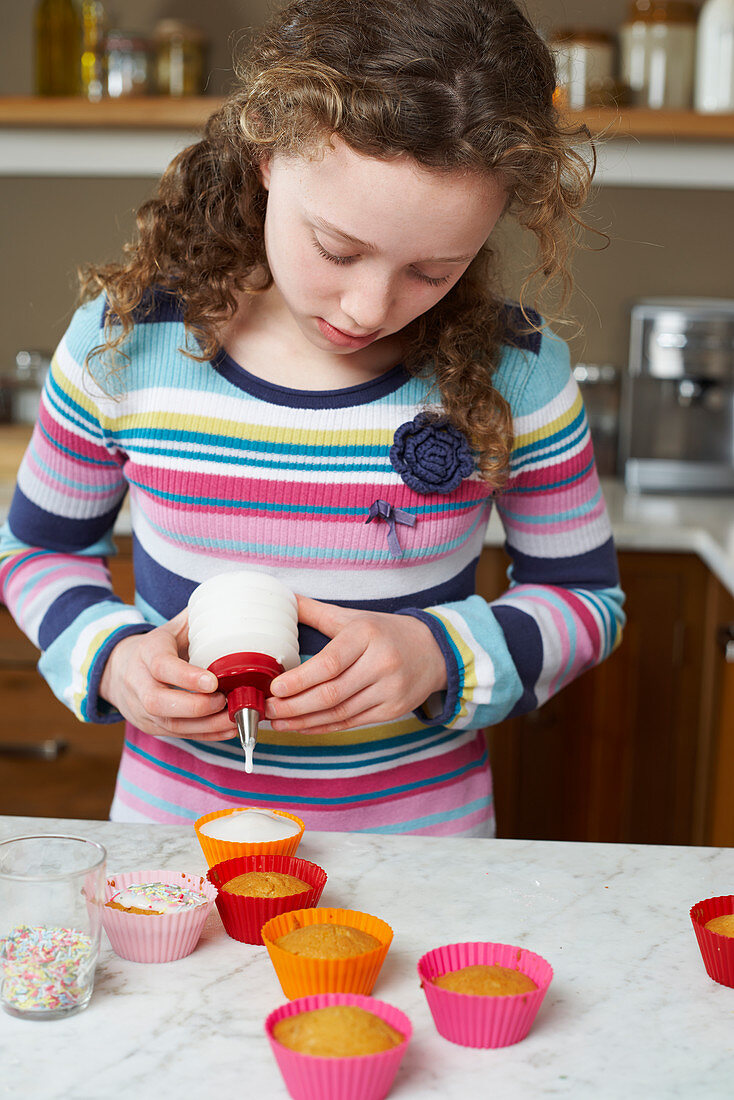 Girl decorating cupcakes in kitchen
