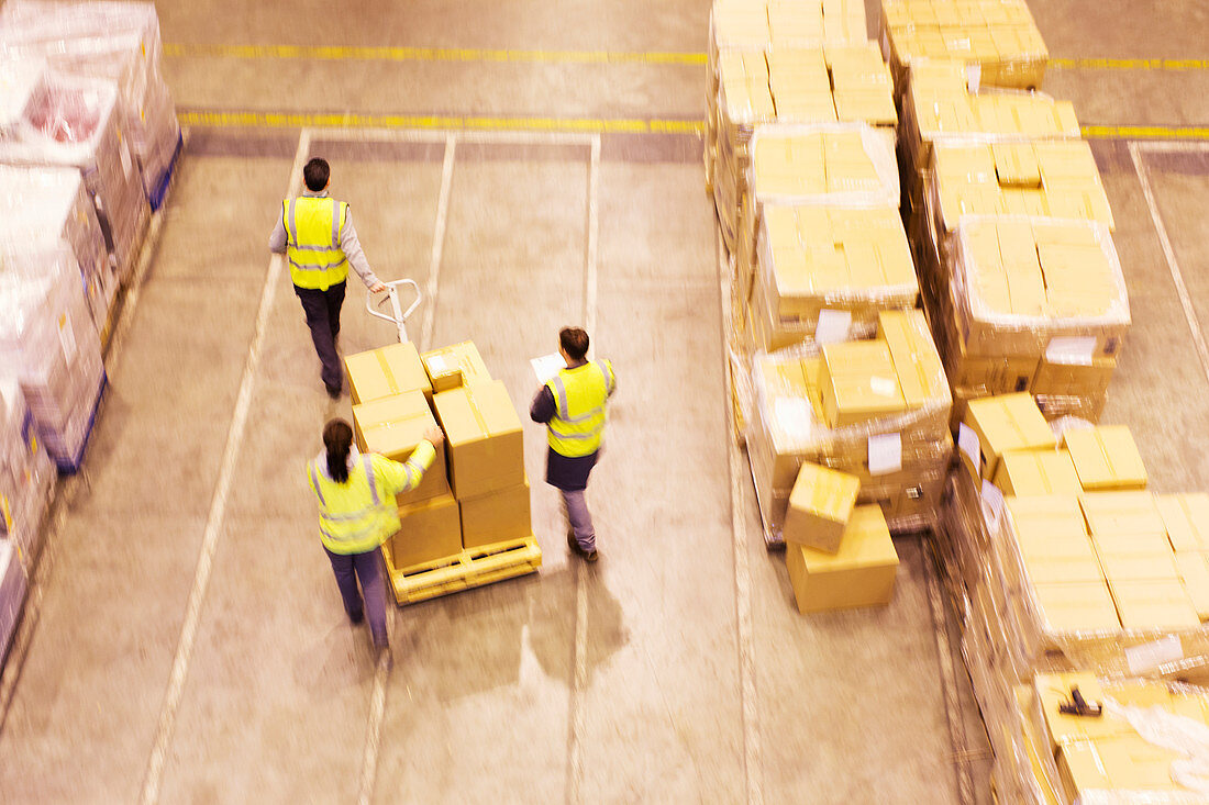 Workers carting boxes in warehouse