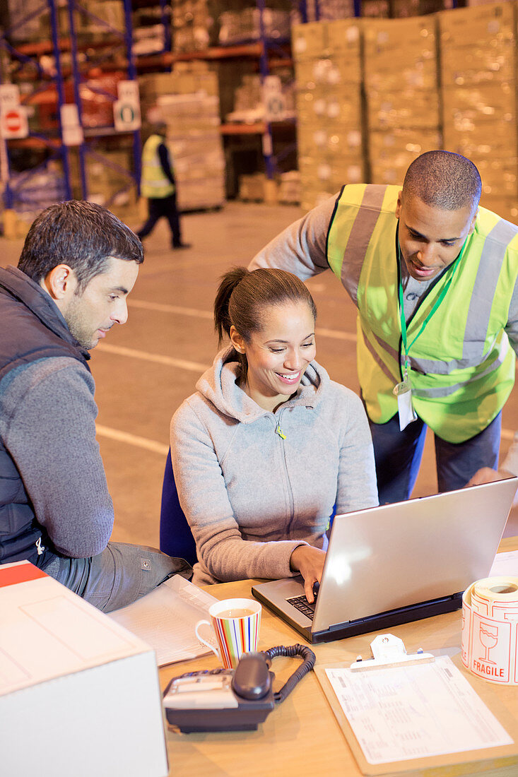 Workers using laptop in warehouse