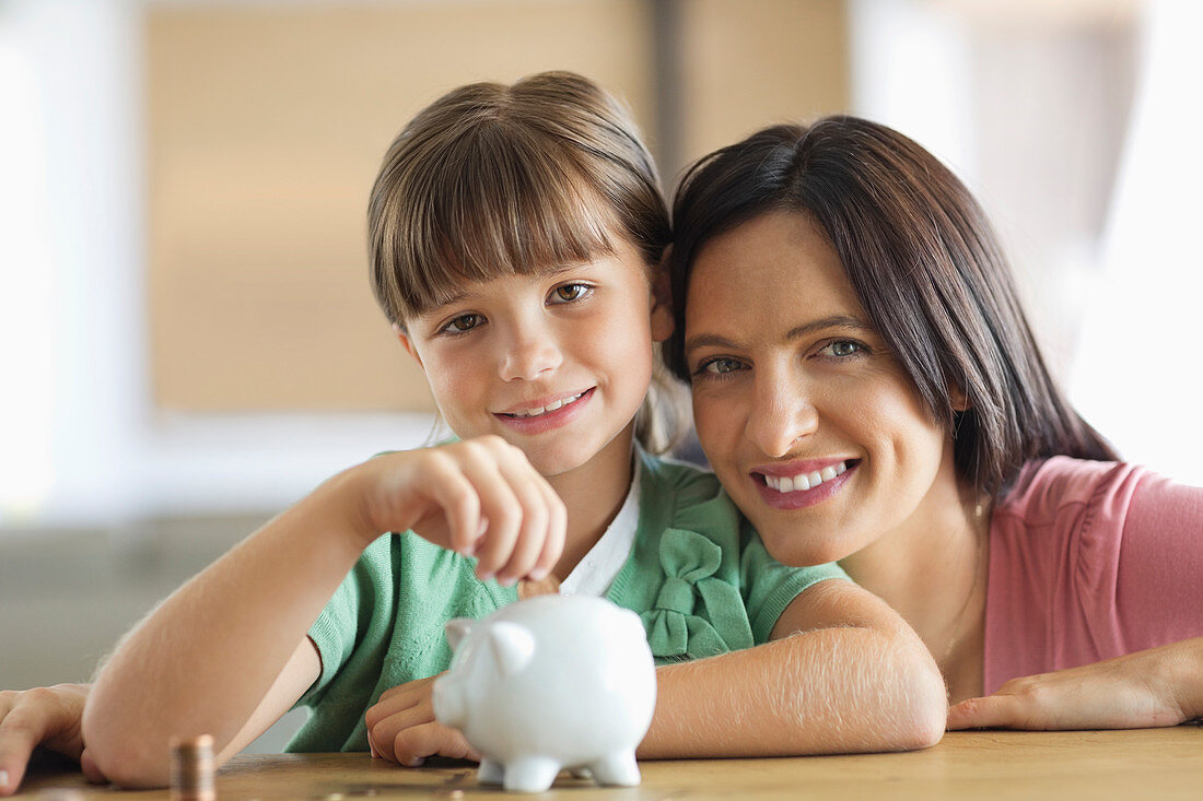 Mother and daughter filling piggy bank