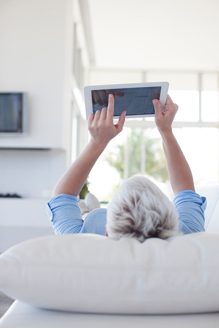 Woman using tablet computer on sofa