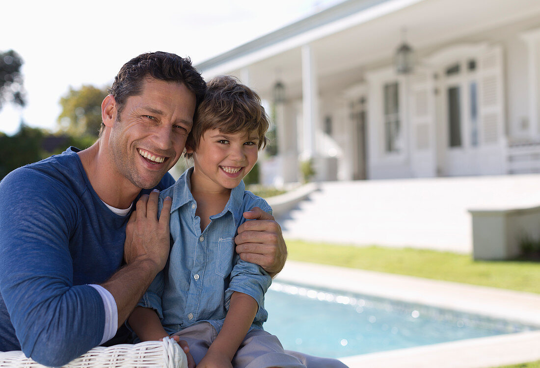 Father and son smiling outside house