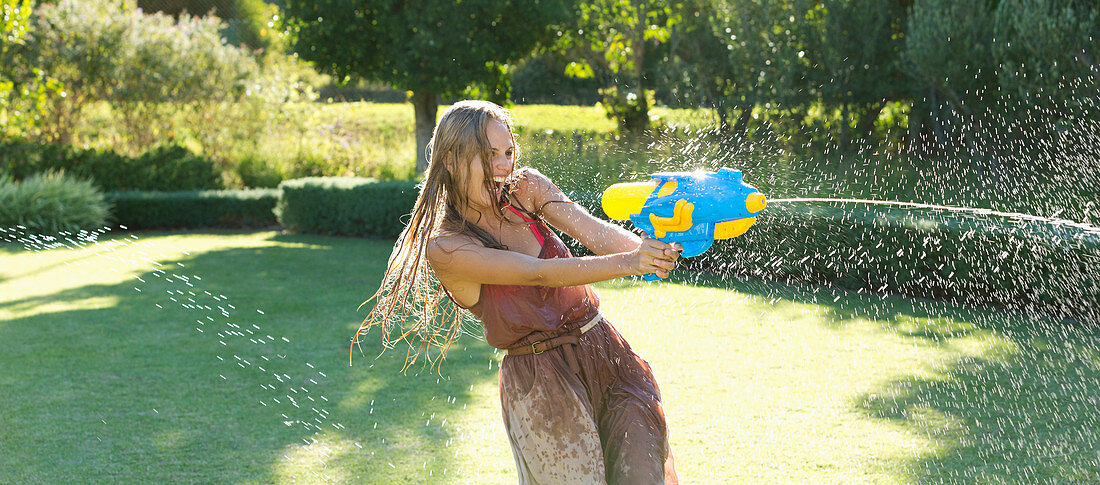 Girl playing with water gun in backyard