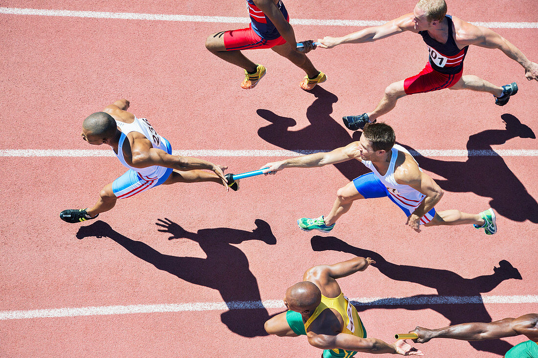 Relay runners passing batons on track