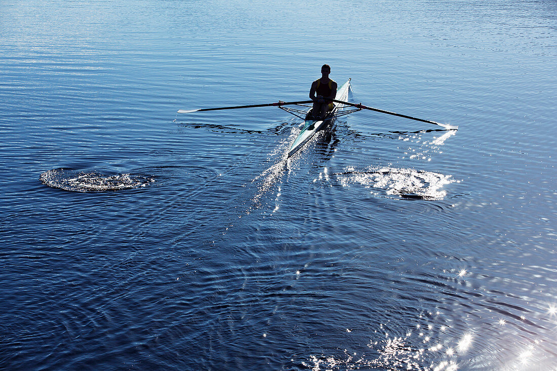 Man rowing scull on lake