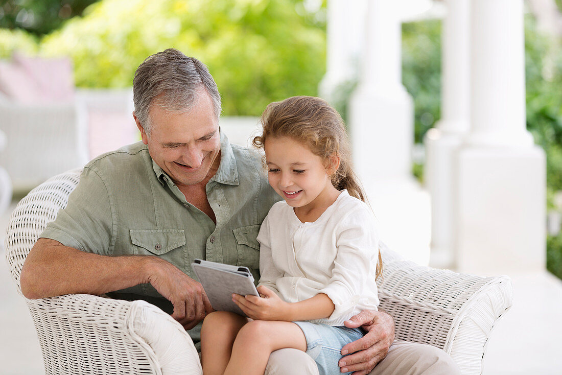 Older man and granddaughter using tablet
