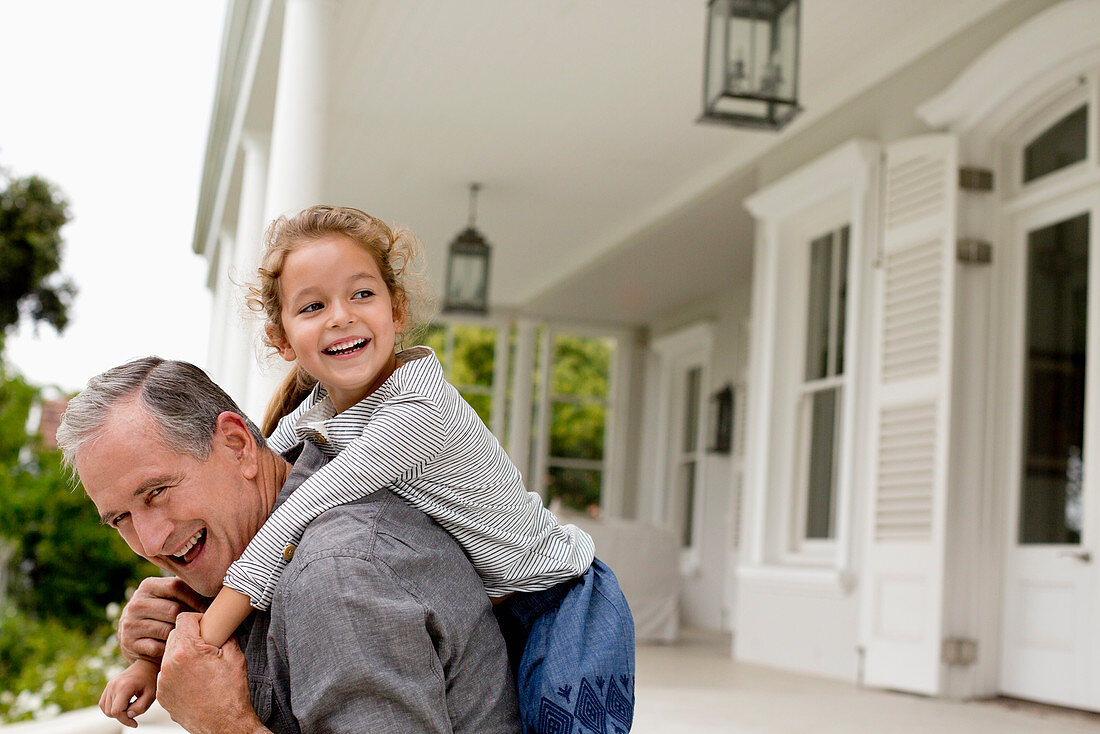 Older man carrying granddaughter