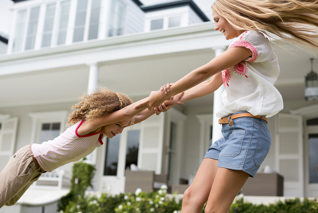 Mother and daughter playing outside house