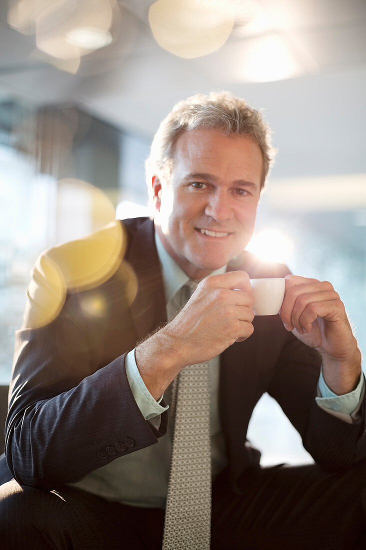 Smiling businessman drinking espresso