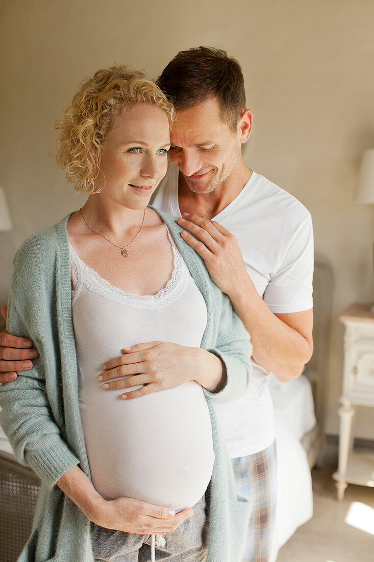 Smiling man hugging pregnant woman