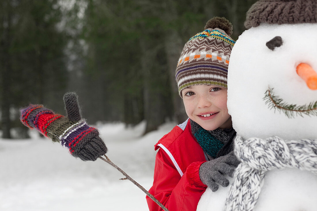 Close up of smiling boy behind snowman