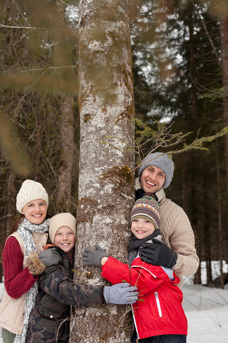 Family hugging tree trunky woods