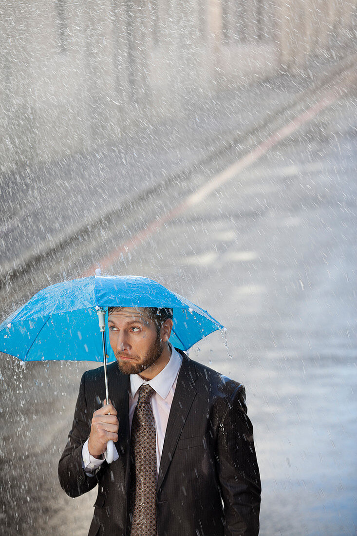 Businessman under tiny umbrella