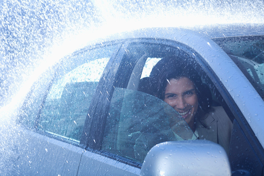 Smiling businesswoman inside car in rain