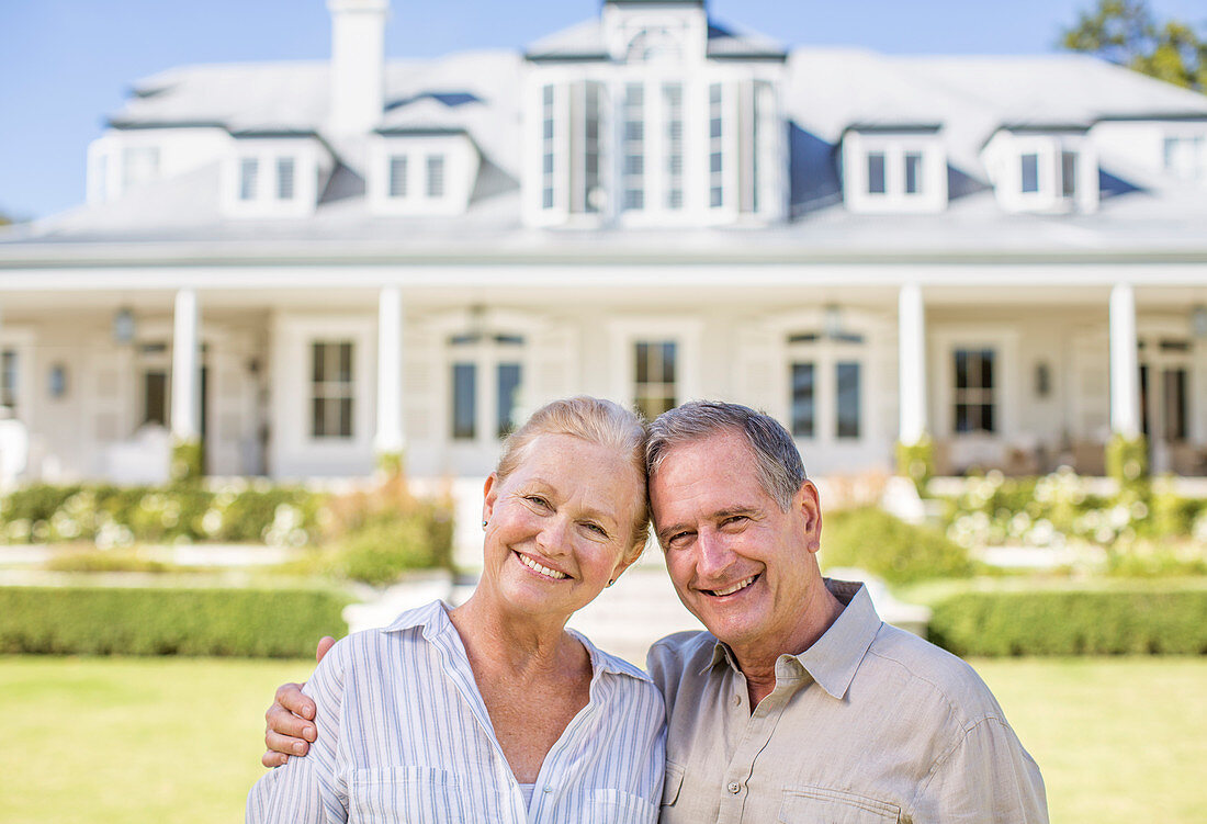 Smiling senior couple in front of house