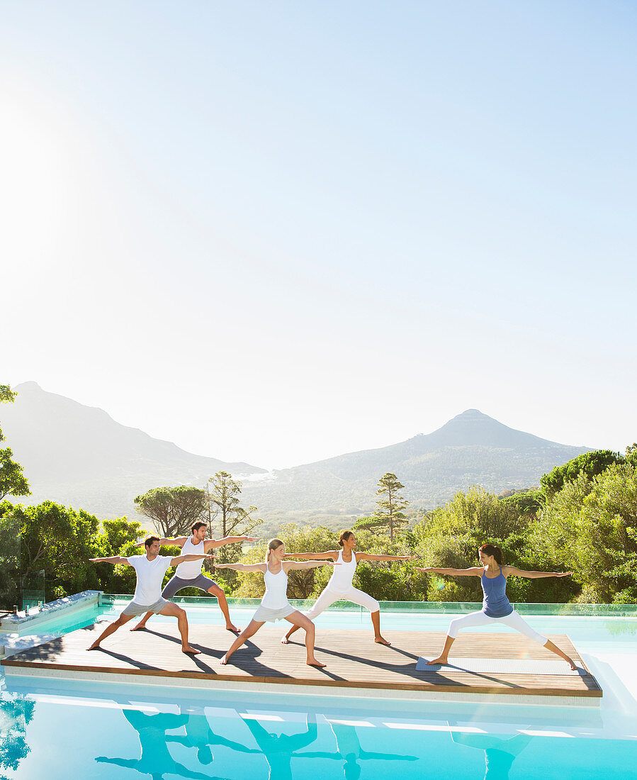 People practicing yoga at poolside