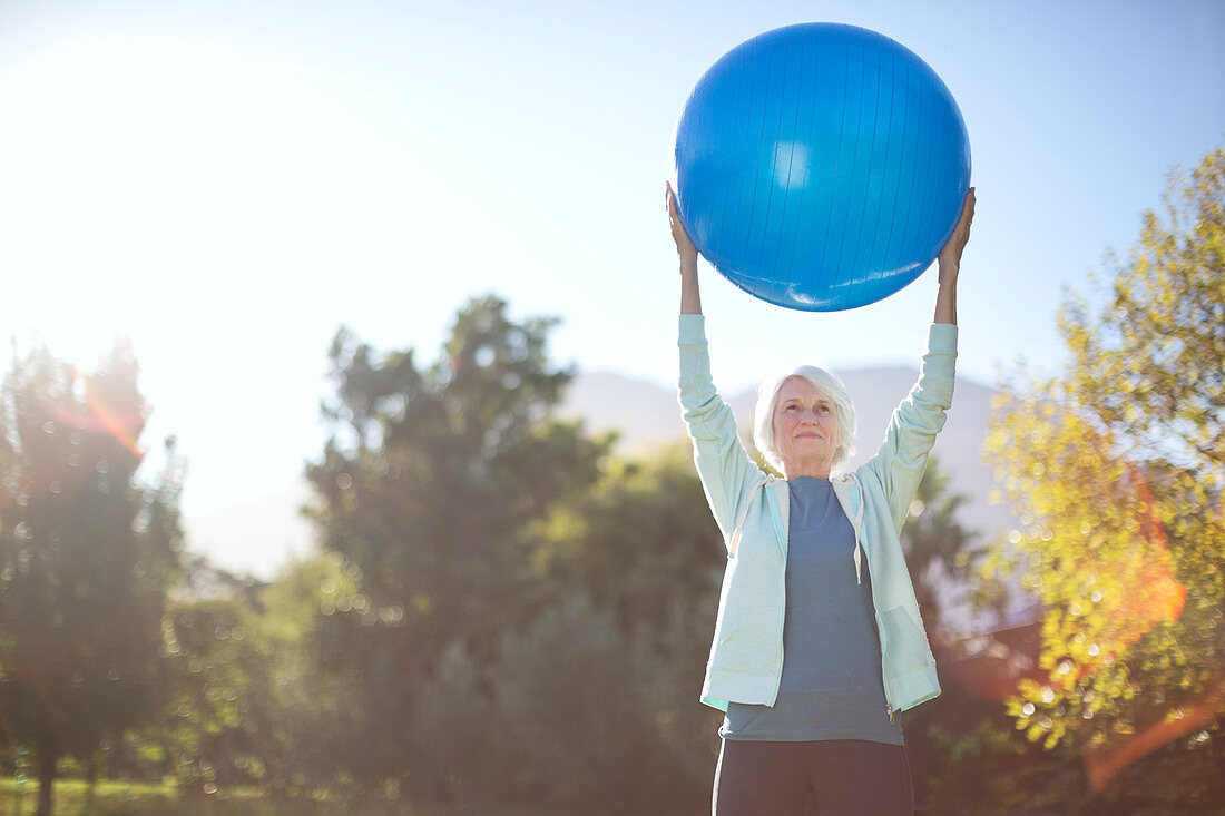 Senior woman holding fitness ball in park