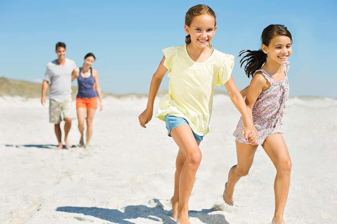 Girls holding hands and running on beach