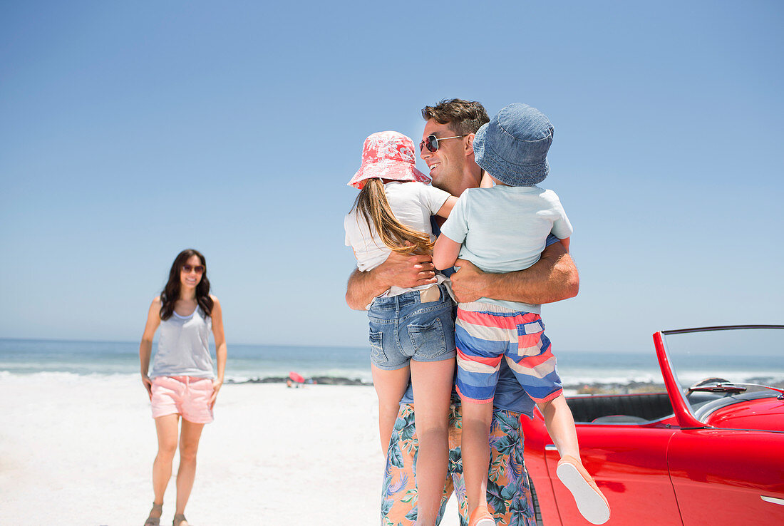 Father holding children on beach