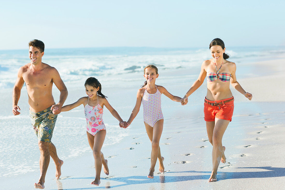 Family holding hands and running on beach