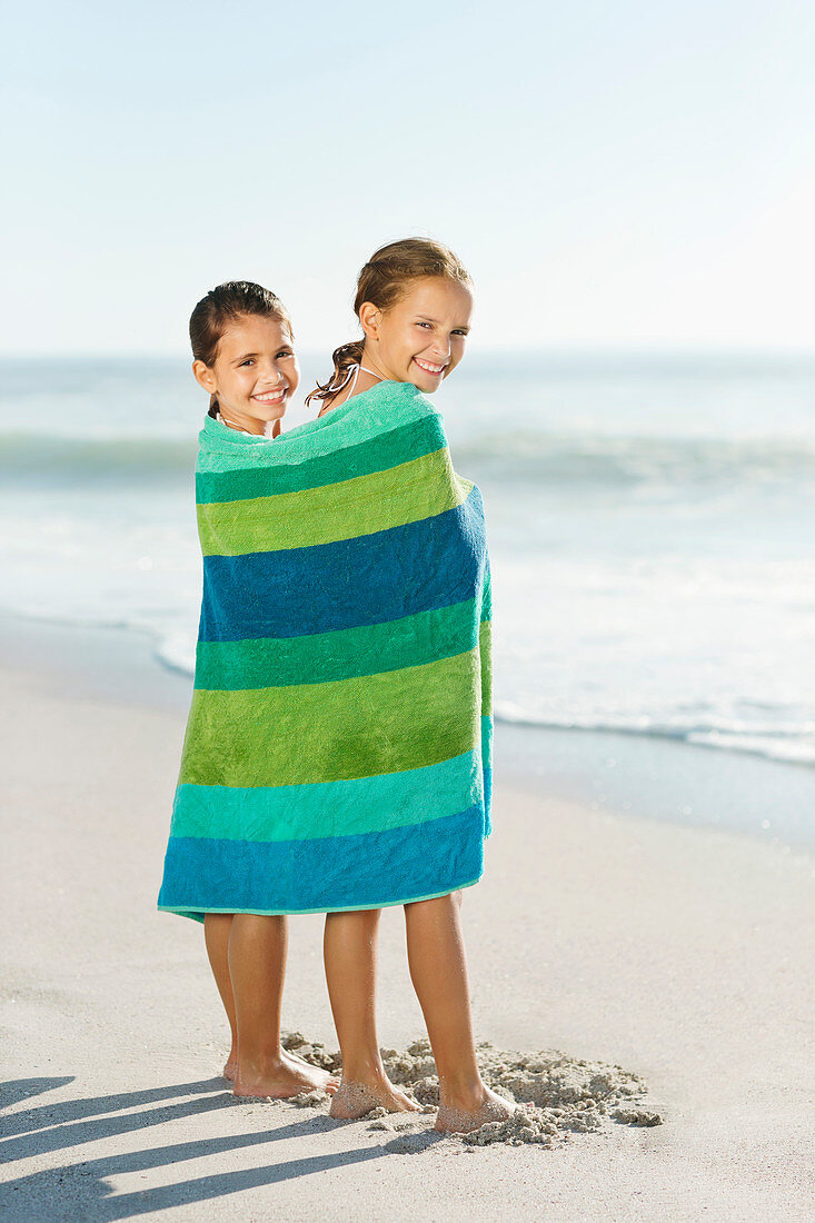 Girls wrapped in towel on beach