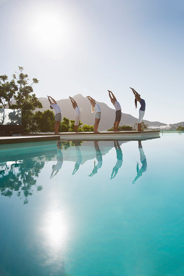 People practicing yoga at poolside