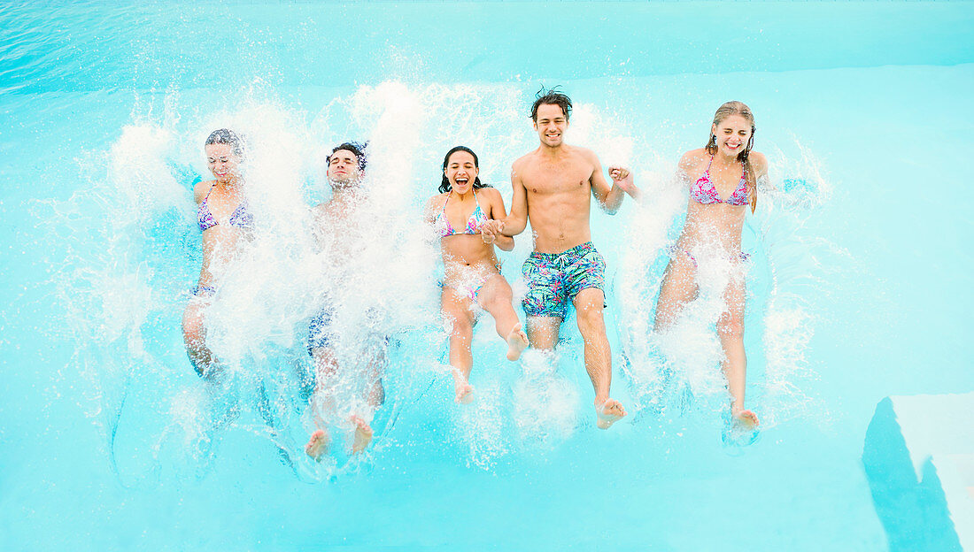 Friends jumping into swimming pool