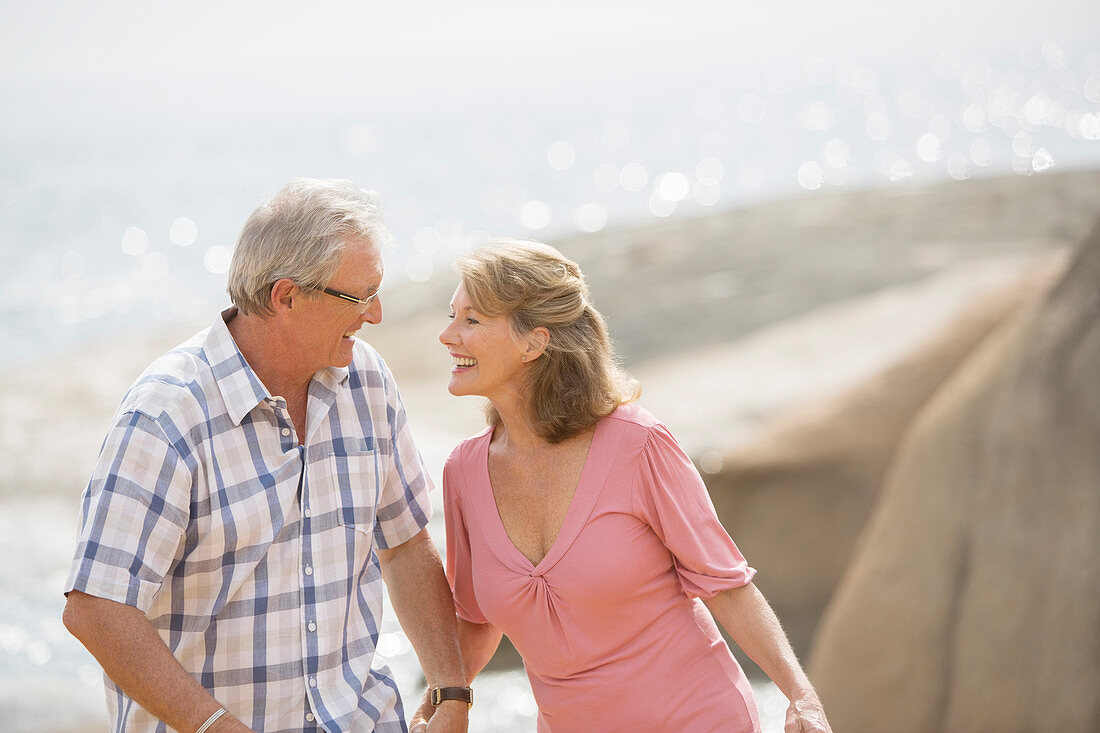 Older couple holding hands on beach