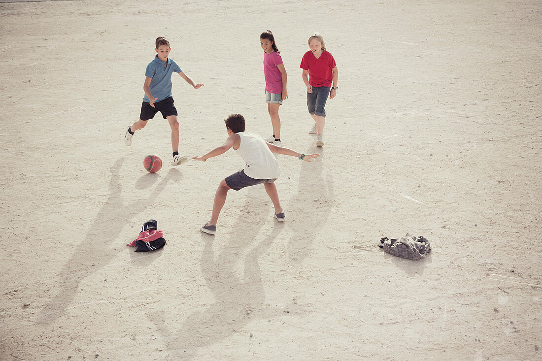 Children playing with soccer ball in sand