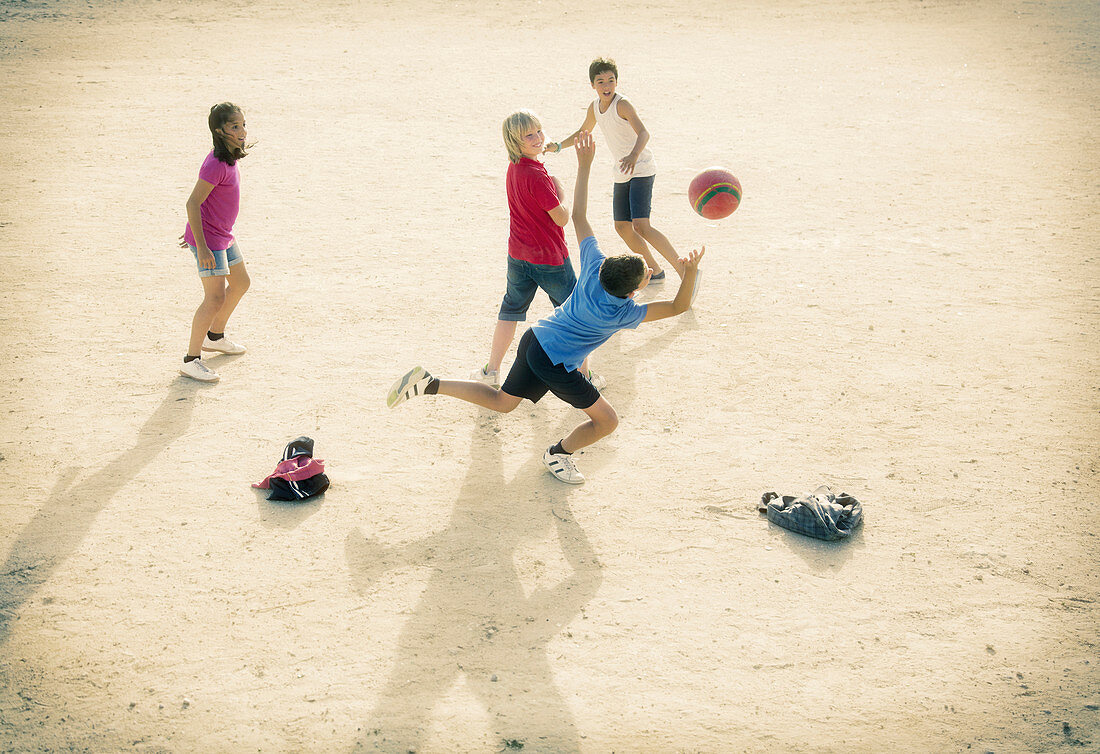 Children playing with soccer ball in sand