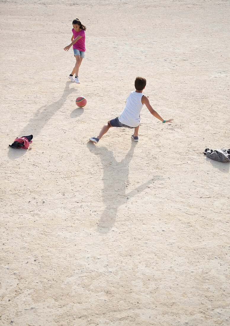 Children playing with soccer ball in sand