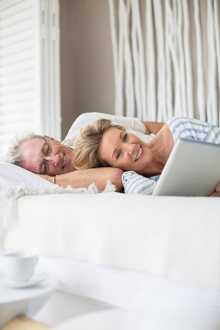 Older couple using digital tablet on bed