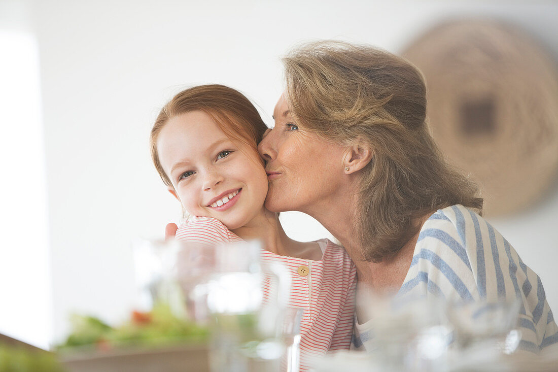 Older woman kissing granddaughter