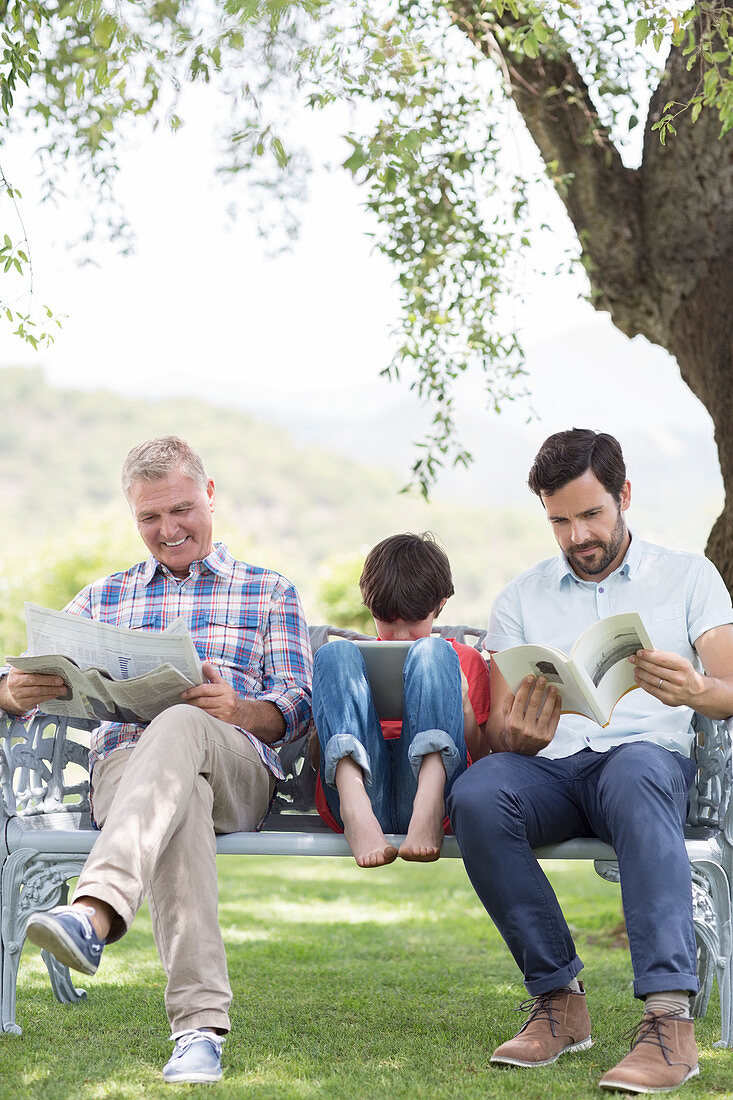 Multi-generation men reading on bench