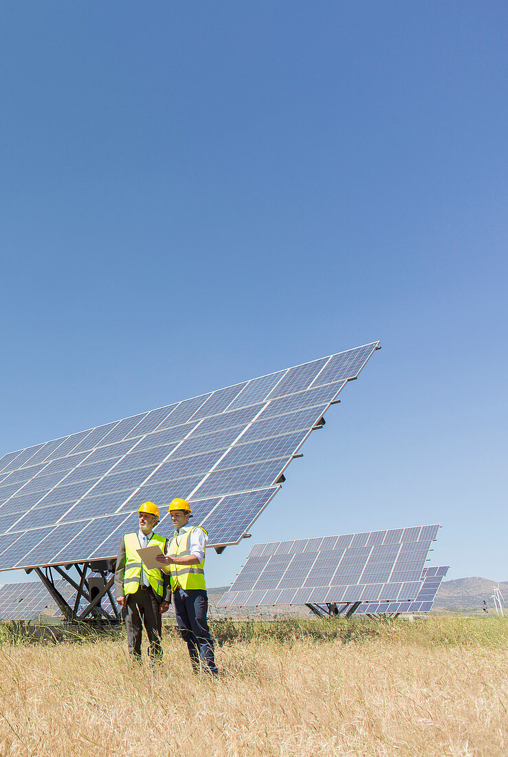 Workers standing by solar panels