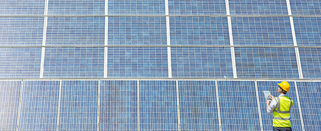 Worker examining solar panel