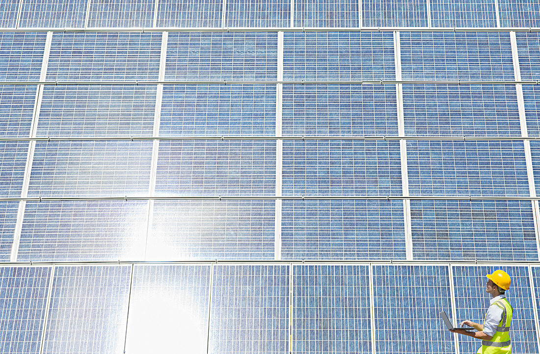 Worker examining solar panel