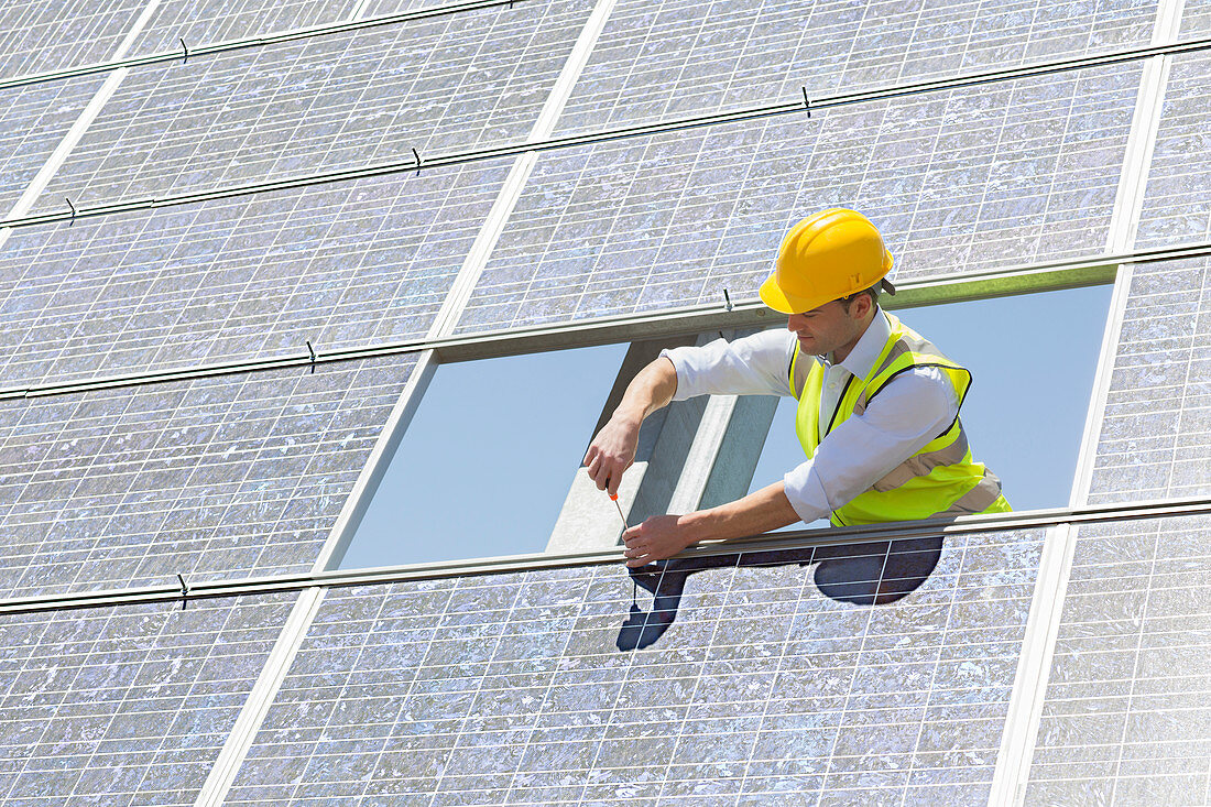 Worker examining solar panel