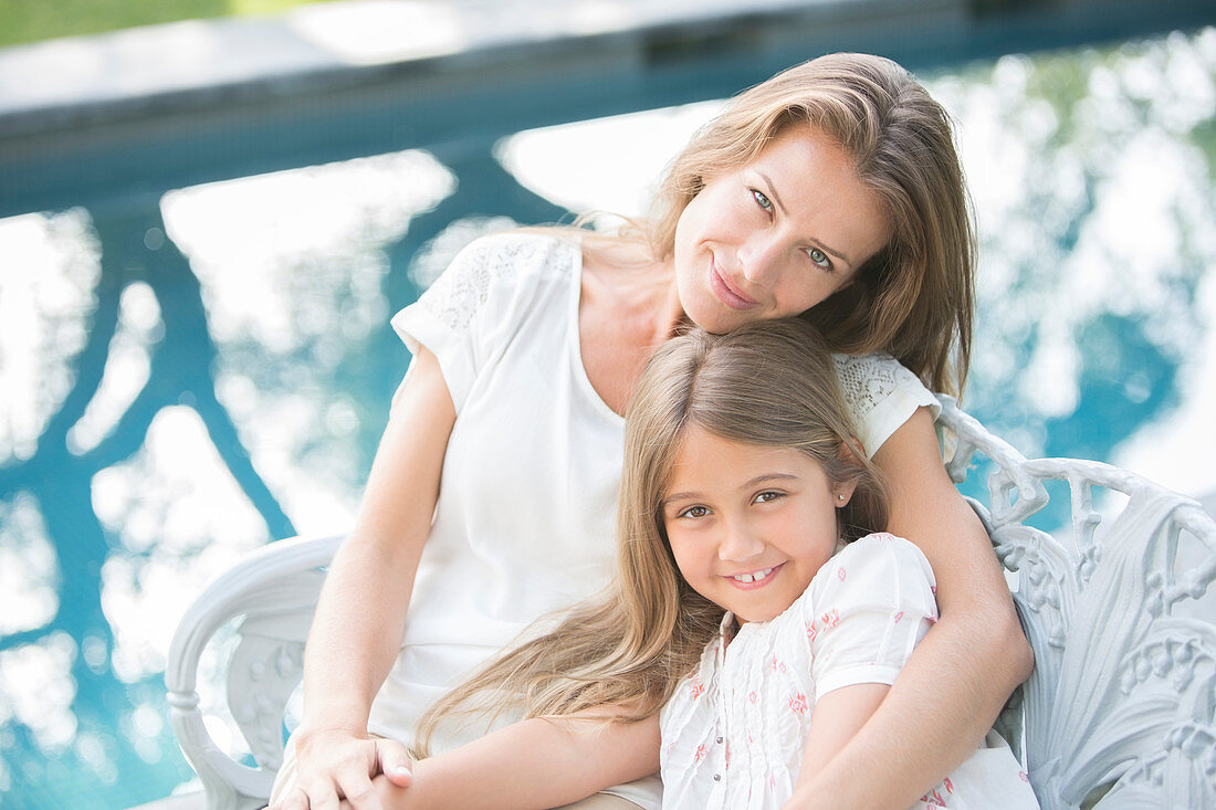 Mother and daughter relaxing at poolside