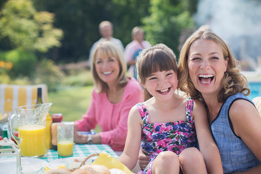 Family laughing at table in backyard